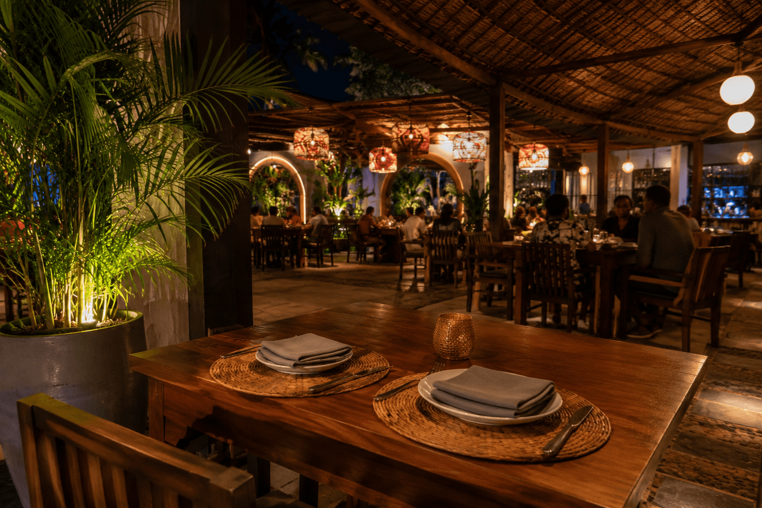 A prepared table set for two in a warm open-sided restaurant.